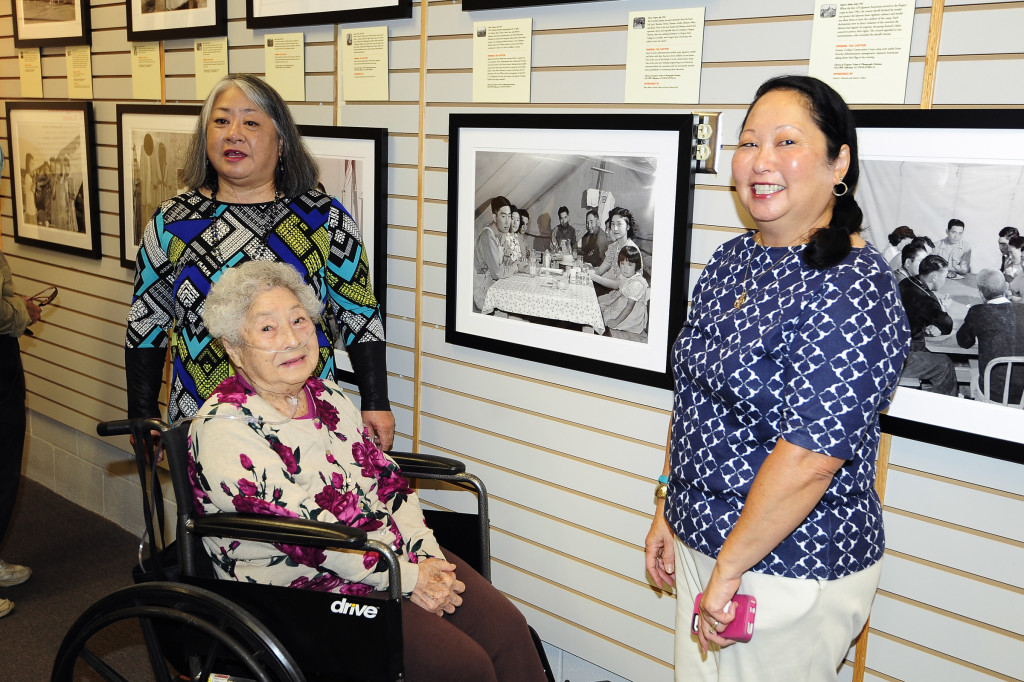 Janet Koda and Carol Takami-Tolman pose with their mother Mary Takami at the opening reception. Mary is featured in the middle photograph, the second woman on the right. Photo courtesy of David Nishitani.
